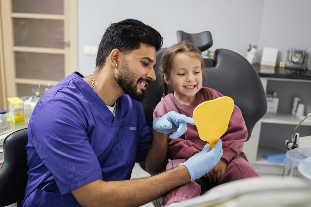 Dental assistant showing little girl her great smile after cleaning